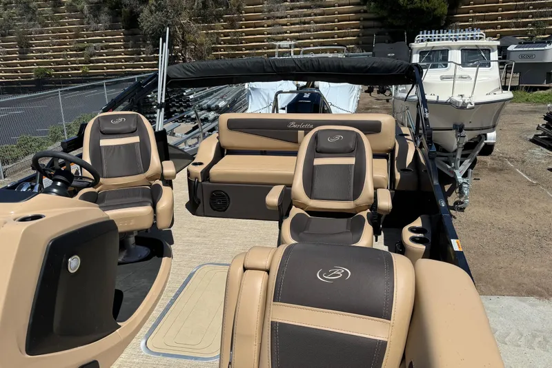 Slide: The Image of 2023 Barletta Cabrio 22UC pontoon boat with tan and brown seating, docked outdoors. - 19