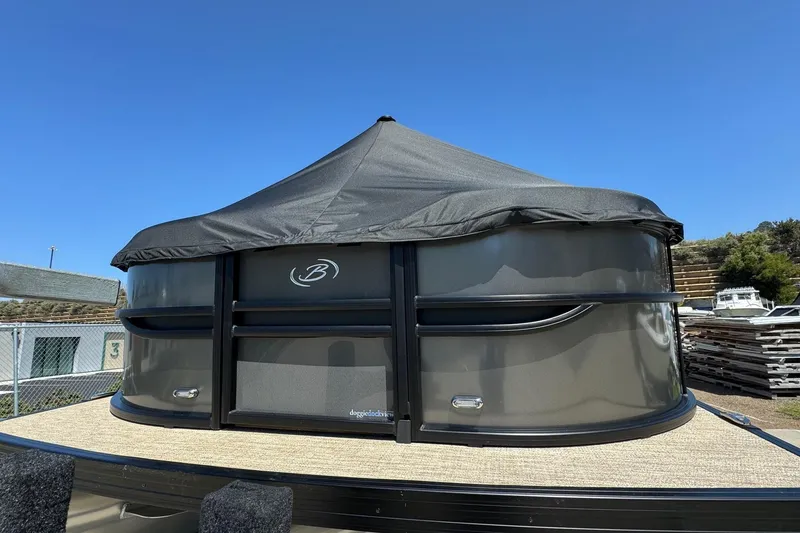 Slide: The Image of 2023 Barletta Cabrio 22UC pontoon boat with black canopy, docked under clear blue sky. - 4