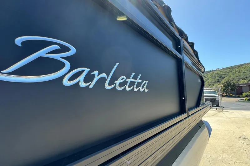 Slide: The Image of 2023 Barletta Cabrio 22UC boat with logo, parked outdoors under clear sky. - 8