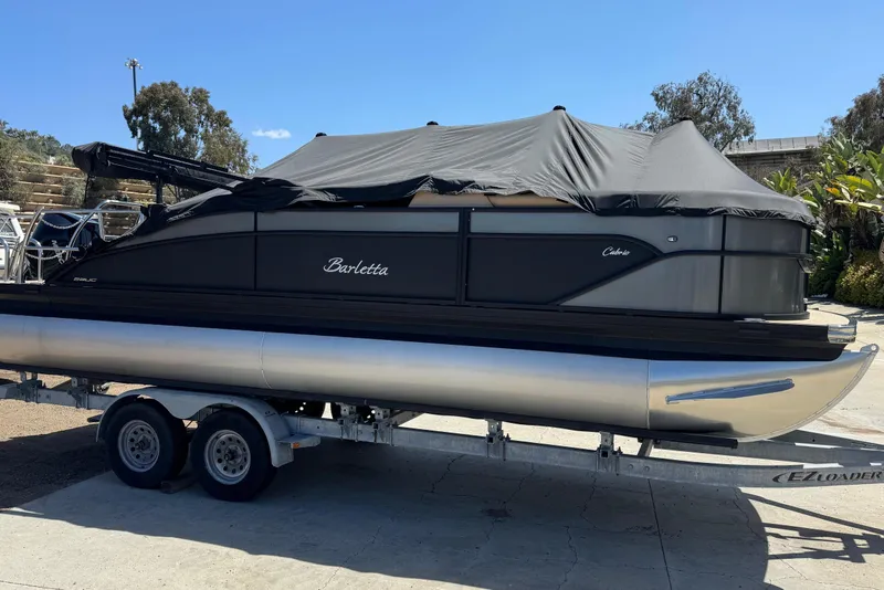 Slide: The Image of 2023 Barletta Cabrio 22UC pontoon boat on trailer, covered, outdoors. - 9
