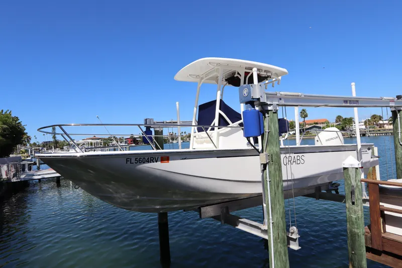 Slide: The Image of 2019 Boston Whaler 210 Montauk boat on lift, docked by waterfront homes. - 2