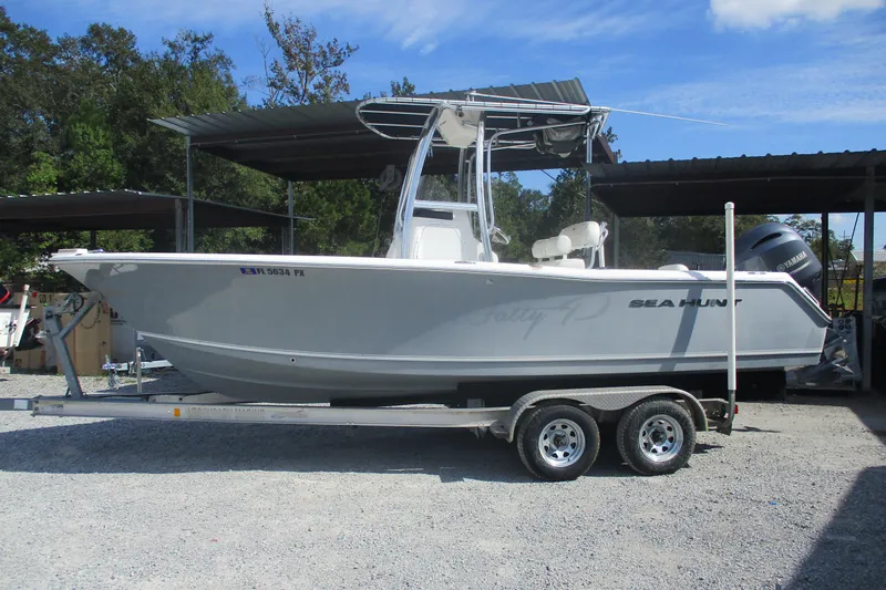 The Image of 2015 Sea Hunt Triton 225 boat on trailer, parked outdoors under a canopy. - 0