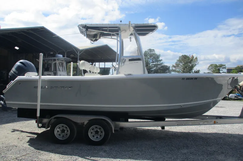 Slide: The Image of 2015 Sea Hunt Triton 225 boat on trailer, parked outdoors under a partly cloudy sky. - 3