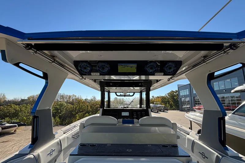 Slide: The Image of 2024 Fountain 38 SCX boat interior with modern dashboard and seating, under clear blue sky. - 28