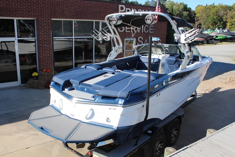 Slide: The Image of 2019 MasterCraft XT22 boat with blue and white design, parked outside a service building. - 4