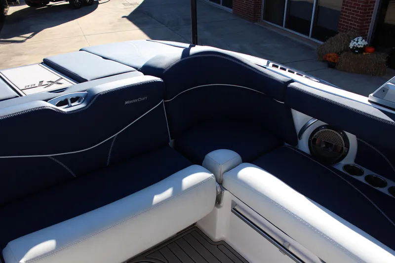 Slide: The Image of 2019 MasterCraft XT22 boat interior with blue and white seating, cup holders, and speaker. - 8