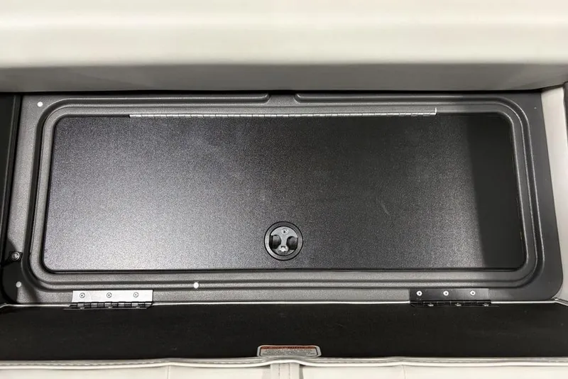 Slide: The Image of 2026 Sun Tracker Fishin' Barge 22 DLX storage compartment with open lid, showcasing interior space. - 27