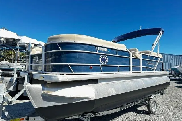 Slide: The Image of 2016 Godfrey Sweetwater 2286 Pontoon boat on trailer, blue and white design, sunny day. - 1