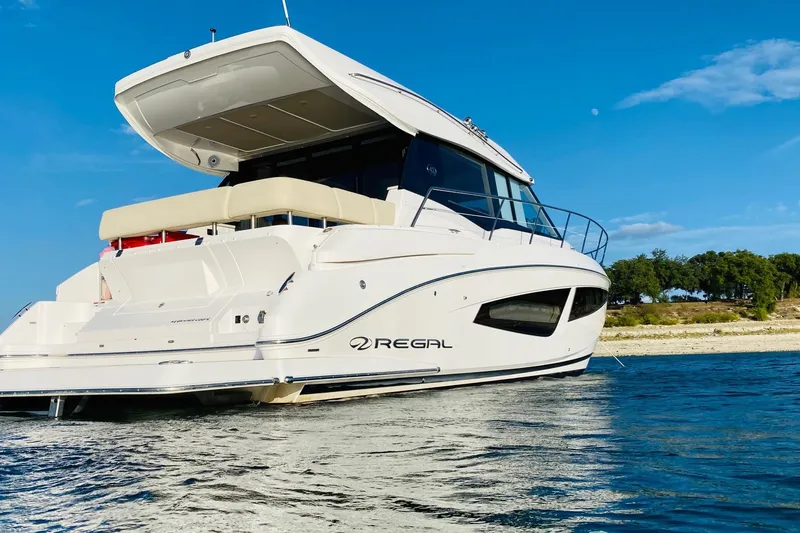 Slide: The Image of 2018 Regal 42 Grande Coupe yacht on calm water under clear blue sky. - 18