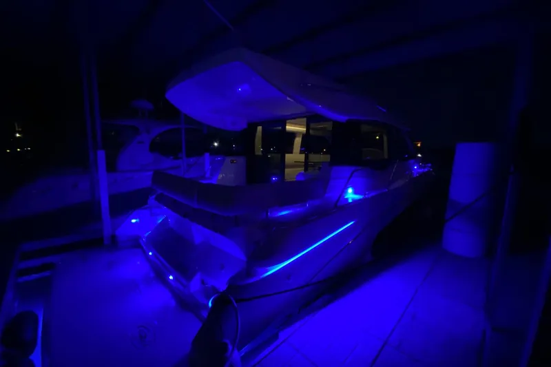 Slide: The Image of 2018 Regal 42 Grande Coupe yacht illuminated with blue lights at night. - 21