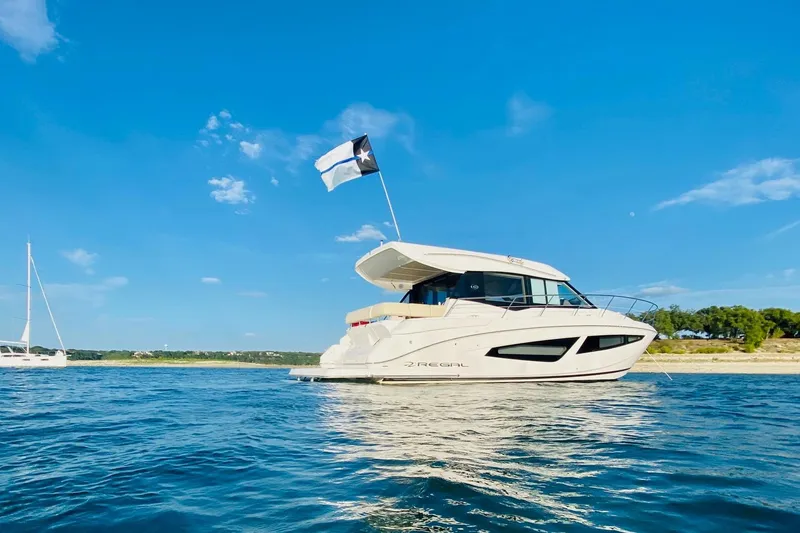 Slide: The Image of 2018 Regal 42 Grande Coupe yacht on calm water under clear blue sky. - 25