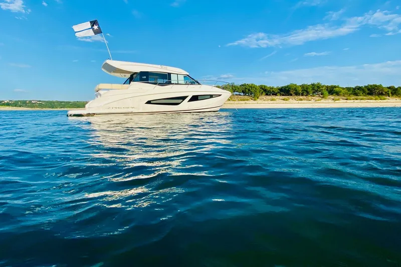 Slide: The Image of 2018 Regal 42 Grande Coupe yacht on calm water under blue sky. - 26