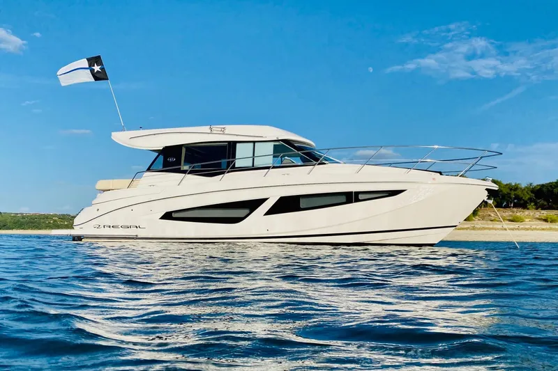 Slide: The Image of 2018 Regal 42 Grande Coupe yacht on calm water under clear blue sky. - 27