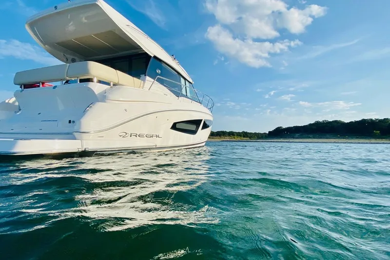 Slide: The Image of 2018 Regal 42 Grande Coupe yacht on serene water under a clear blue sky. - 28
