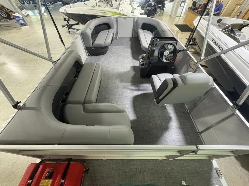 Slide: The Image of 2026 Sun Tracker PARTY BARGE® 16 DLX interior with gray seating and steering console. - 19