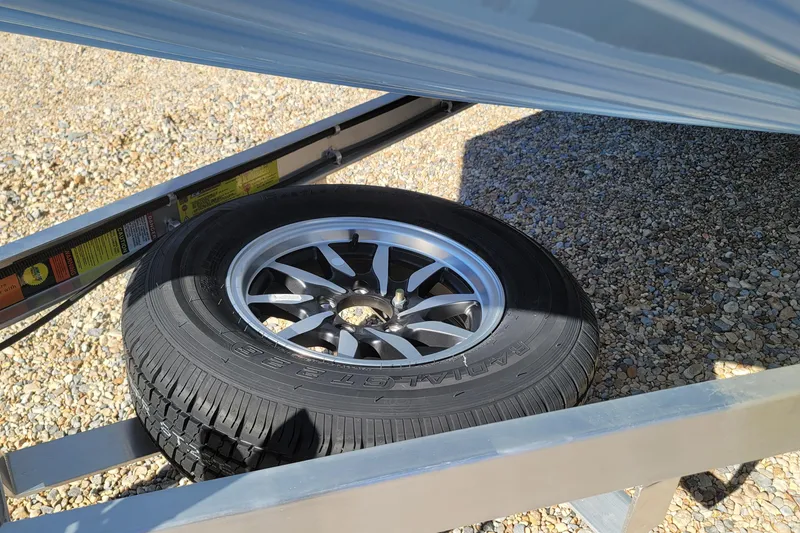 Slide: The Image of Spare tire under G3 Bay 20 boat trailer, 2026 model, on gravel surface. - 17