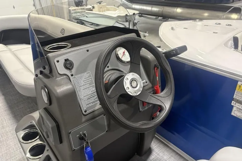 Slide: The Image of 2026 Sun Tracker Party Barge 16 DLX steering console with cup holders and gauges. - 16
