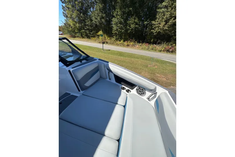 Slide: The Image of 2023 Axis T220 boat interior with gray seating and speaker, parked outdoors. - 10