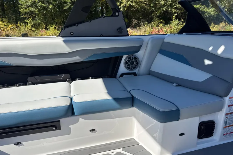 Slide: The Image of 2023 Axis T220 boat interior with gray seating and cup holders, surrounded by greenery. - 11
