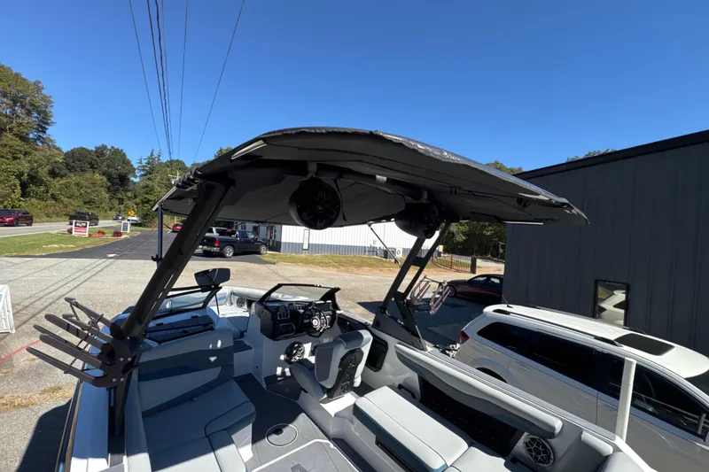 Slide: The Image of 2023 Axis T220 boat with canopy and speakers, parked outdoors under clear blue sky. - 16