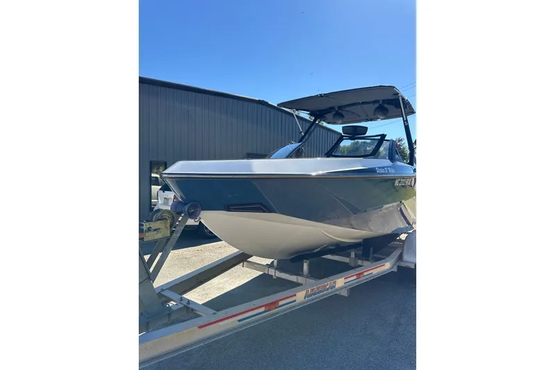 Slide: The Image of 2023 Axis T220 boat with tower speakers and seating, parked outdoors under clear blue sky. - 17