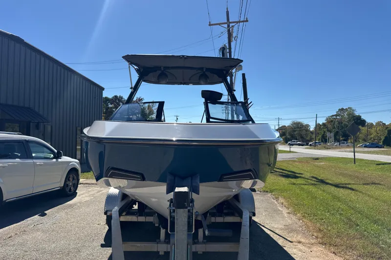 Slide: The Image of 2023 Axis T220 boat with canopy, parked on a trailer under clear blue sky. - 23
