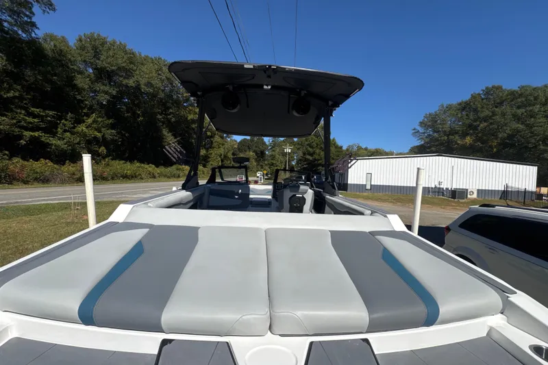 Slide: The Image of 2023 Axis T220 boat with cushioned seating, parked outdoors under clear blue sky. - 5