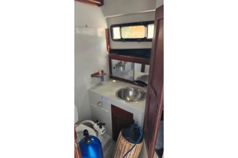 Slide: The Image of 1987 Rampage 28 Sportsman boat bathroom with sink, toilet, and wooden cabinetry. - 27