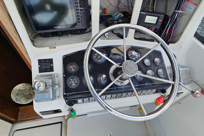 Slide: The Image of 1987 Rampage 28 Sportsman boat docked on a calm waterway under a cloudy sky. - 9