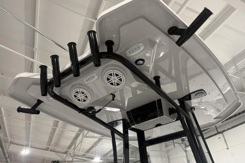 Slide: The Image of 2026 Tidewater 2300 Carolina Bay boat T-top with rod holders and speakers in a showroom. - 27
