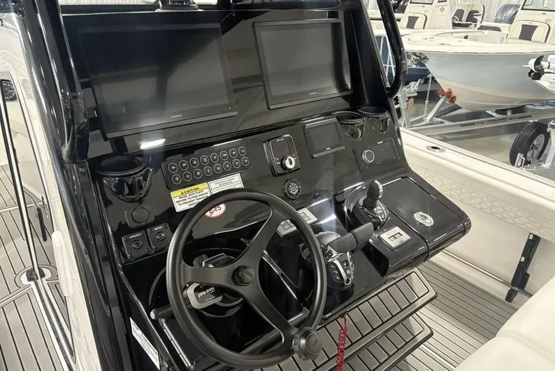 Slide: The Image of 2026 Tidewater 3100 Carolina Bay boat dashboard with steering wheel and control panels. - 16