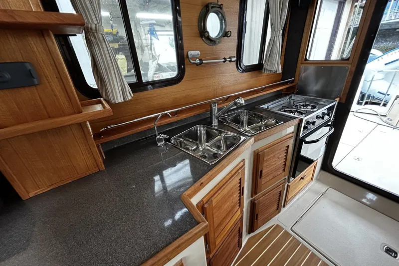 Slide: The Image of 2015 Ranger Tugs R-31 CB interior kitchen with wood cabinetry and stainless steel sink. - 10