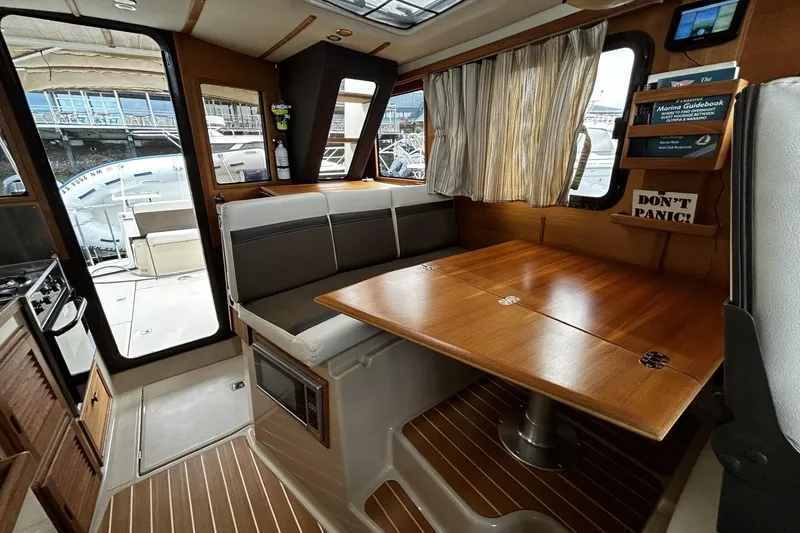 Slide: The Image of 2015 Ranger Tugs R-31 CB interior with dining area and wooden table. - 11