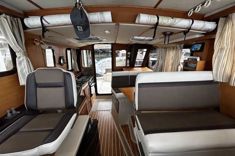 Slide: The Image of Interior of 2015 Ranger Tugs R-31 CB with seating, wood accents, and nautical charts. - 13
