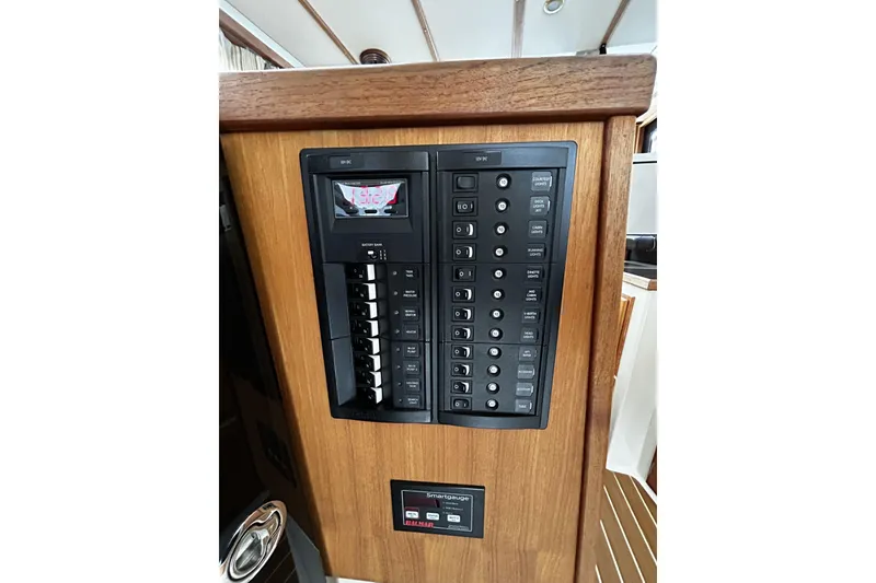 Slide: The Image of 2015 Ranger Tugs R-31 CB electrical panel with switches and display on wooden interior. - 15
