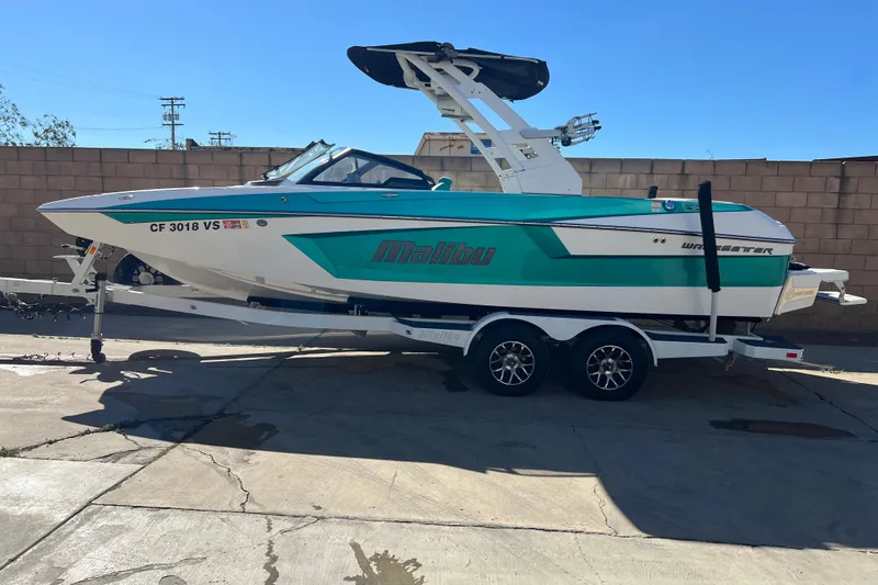The Image of 2020 Malibu Wakesetter 23 MXZ boat on trailer, teal and white design. - 0