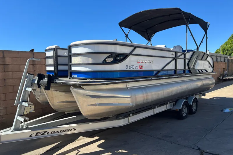 Slide: The Image of 2020 Crest Caribbean RS 250 SLRC pontoon boat on trailer, parked outdoors. - 1