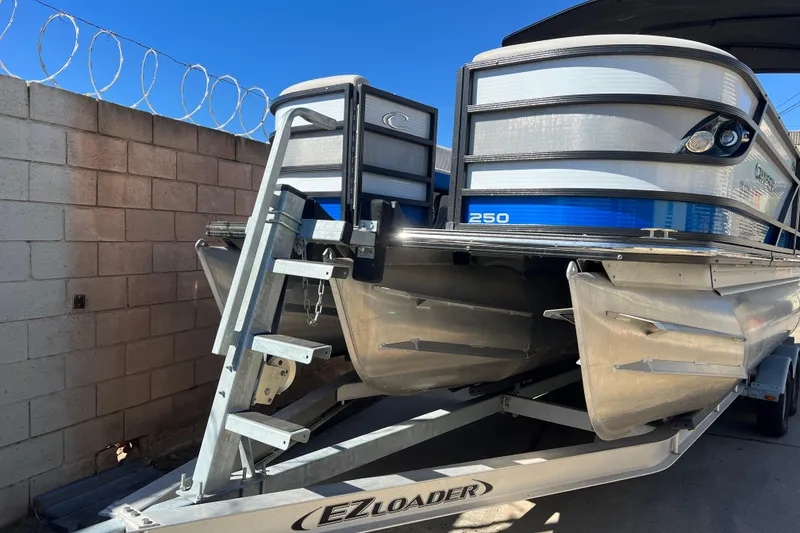 Slide: The Image of 2020 Crest Caribbean RS 250 SLRC pontoon boat on EZ Loader trailer, parked by a brick wall. - 3