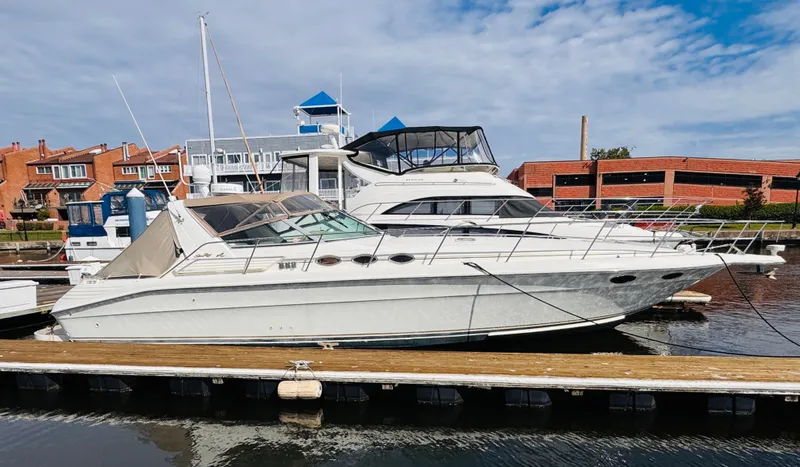 The Image of 1995 Sea Ray 400 Express Cruiser docked at marina, clear sky background. - 0
