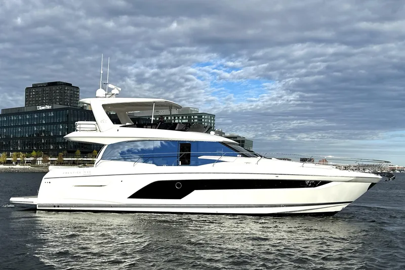 The Image of 2023 Prestige 590 yacht cruising on a river with cityscape background. - 0