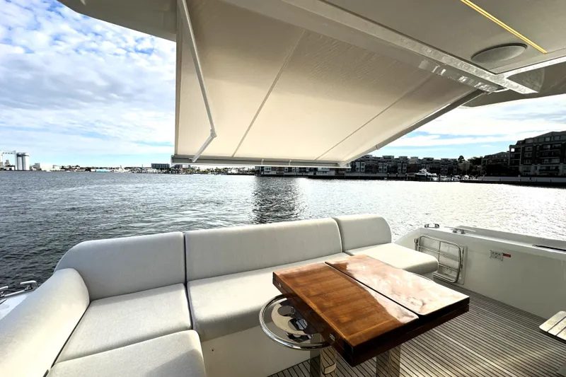 Slide: The Image of Luxurious 2023 Prestige 590 yacht deck with seating, table, and waterfront view. - 14