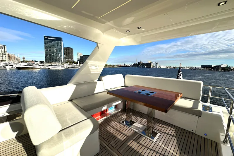 Slide: The Image of Luxurious 2023 Prestige 590 yacht deck with seating, table, and waterfront city view. - 23