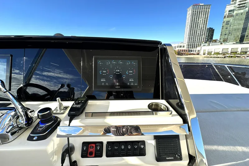 Slide: The Image of 2023 Prestige 590 yacht helm with modern controls and cityscape background. - 34
