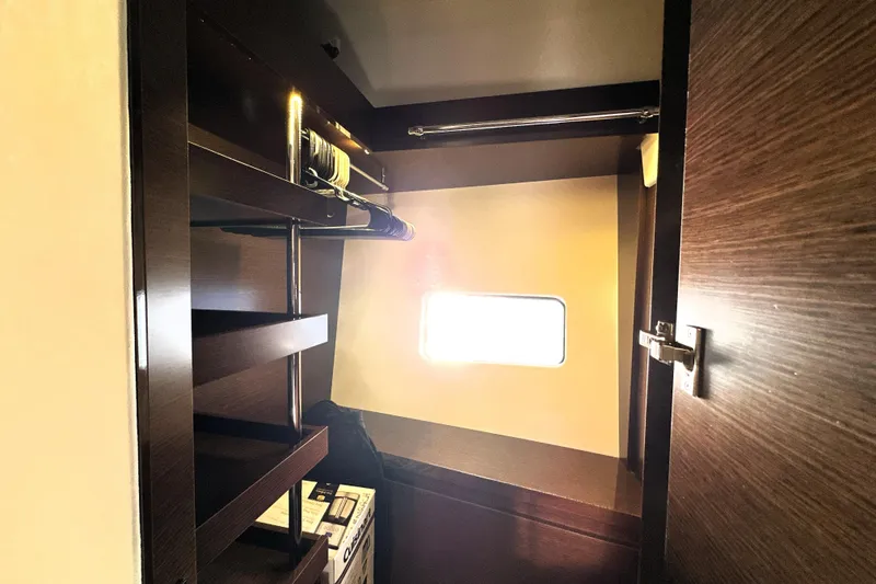 Slide: The Image of Interior of 2023 Prestige 590 yacht closet with shelves and window. - 62