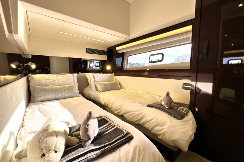 Slide: The Image of Luxurious twin cabin interior on 2023 Prestige 590 yacht, featuring plush bedding and elegant decor. - 65