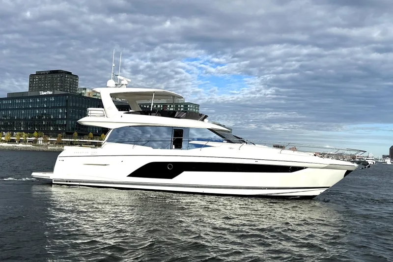 Slide: The Image of 2023 Prestige 590 yacht cruising on a river with cityscape background. - 7