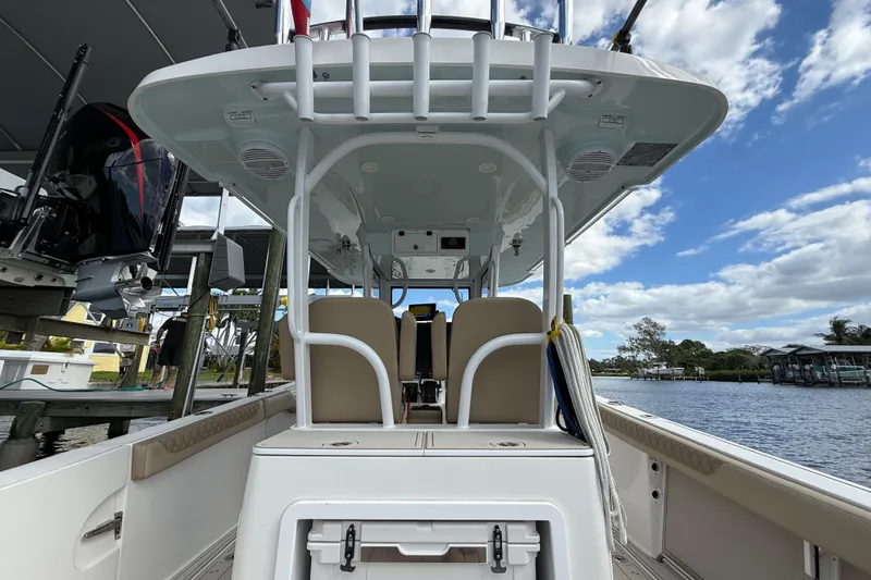 Slide: The Image of 2023 Sea Pro 320 DLX Offshore boat interior with seating and storage, docked by a scenic waterfront. - 25