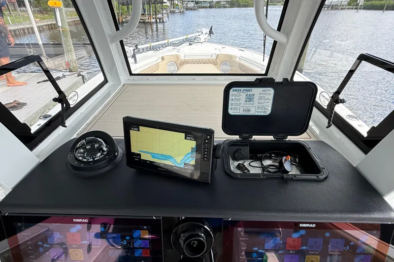 Slide: The Image of 2023 Sea Pro 320 DLX Offshore boat dashboard with navigation equipment and scenic water view. - 52