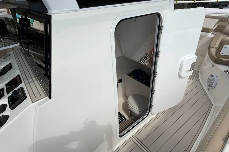 Slide: The Image of 2023 Sea Pro 320 DLX Offshore boat interior with open cabin door and visible toilet. - 60