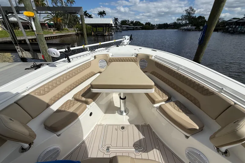 Slide: The Image of 2023 Sea Pro 320 DLX Offshore boat interior with seating and table, docked by a scenic waterfront. - 67